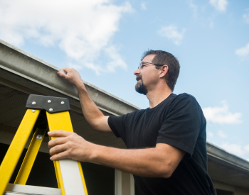 A Pacific homeowner inspecting roof shingles for damage.